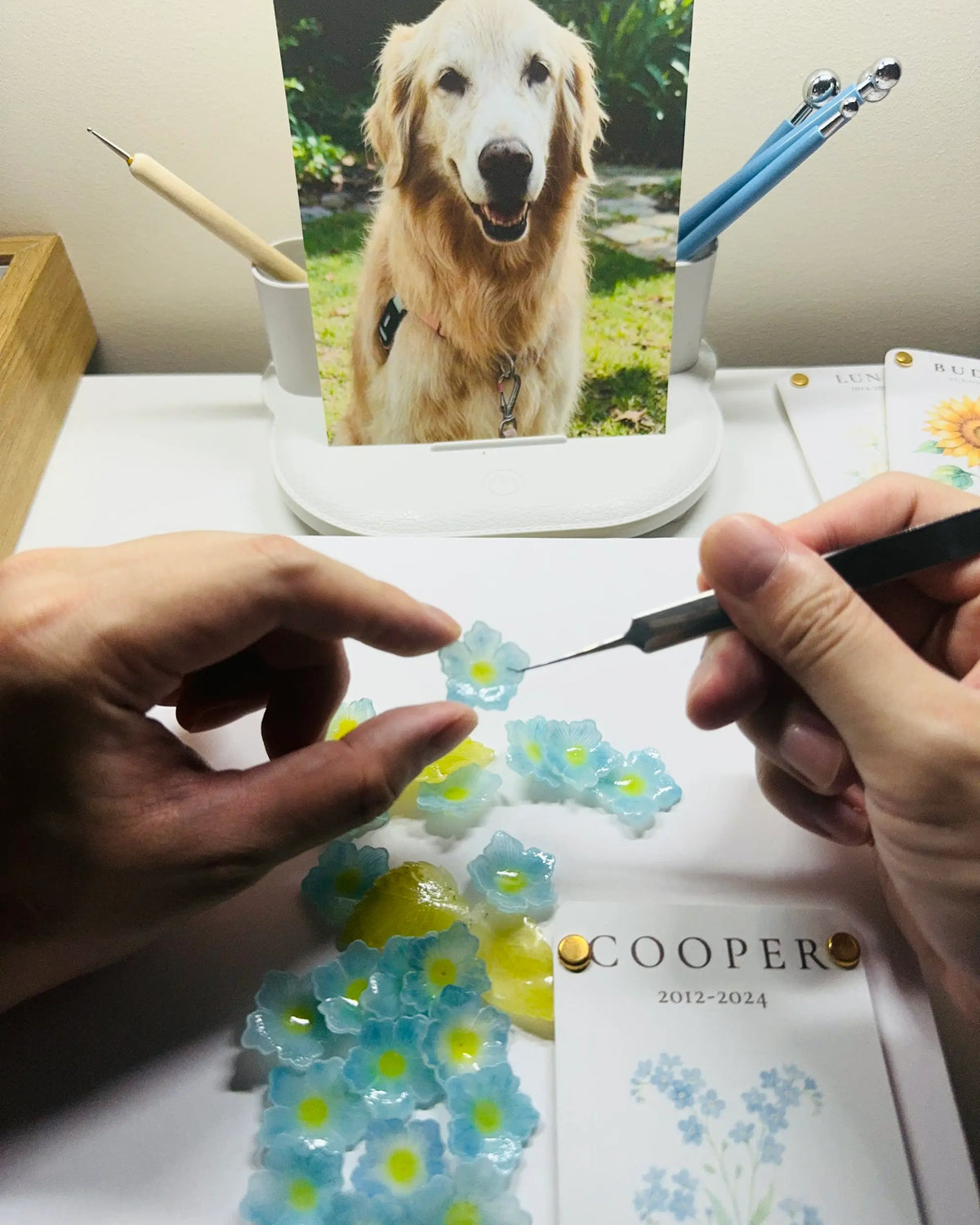 Hands carefully shaping a handmade blue flower with a precision tool