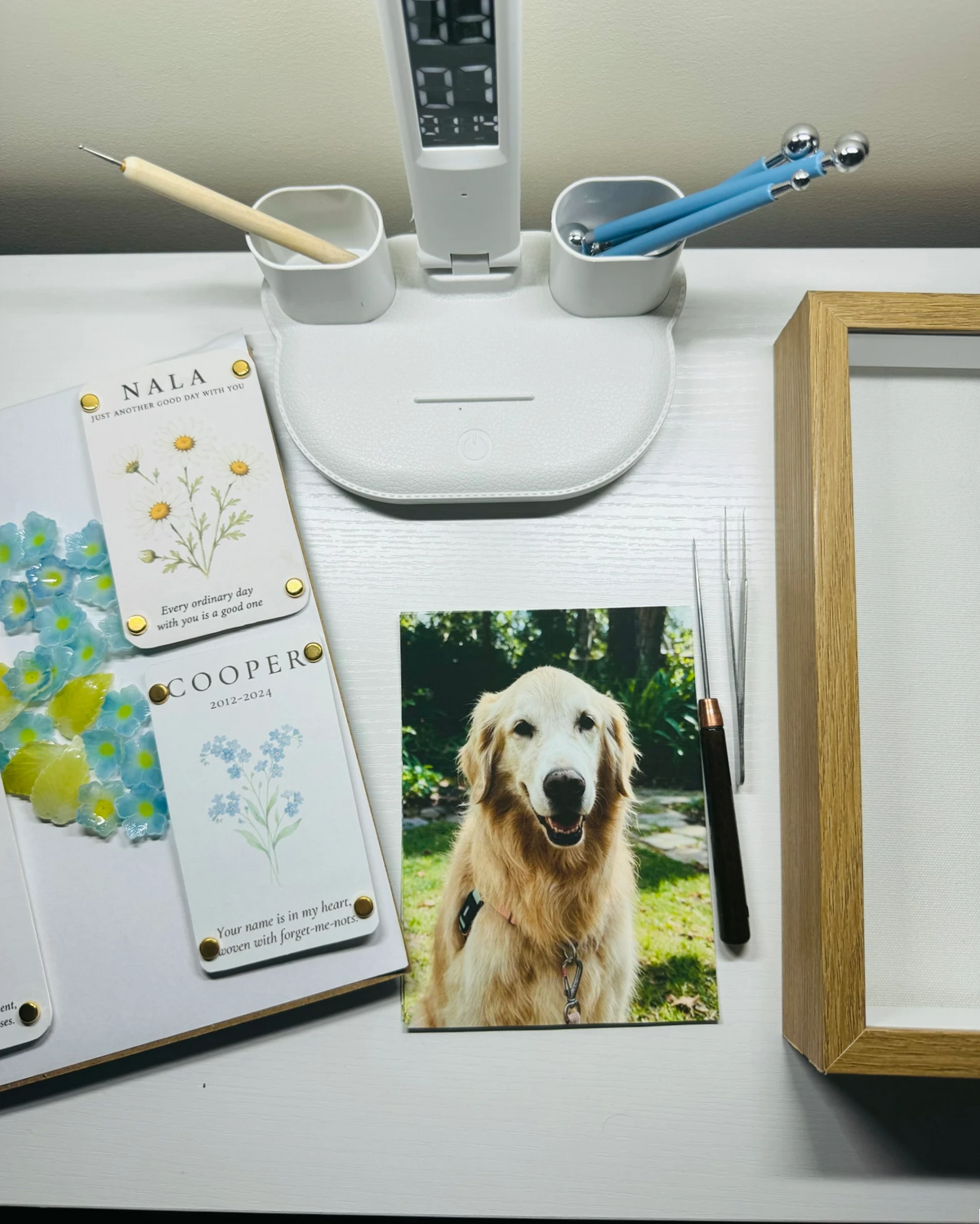 Pet photograph, personalized cards, handmade flowers, and tools arranged on a studio worktable